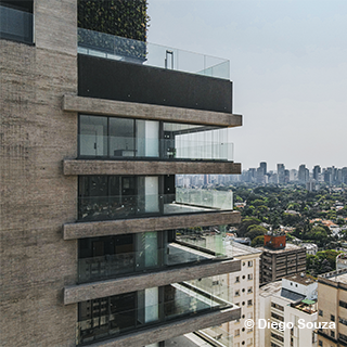 Foto de uma área de lazer, com mesa de madeira no primeiro plano, ilha de mármore à esquerda e sofás azuis no fundo.